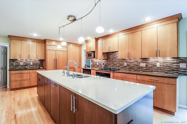 9 Maplewood Dr, Danbury, CT 06811 - kitchen with built in appliances, tasteful backsplash, light wood-style floors, a center island with sink, and decorative light fixtures