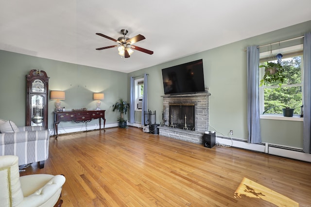 98 Aetna Ave, Torrington, CT 06790 - living room with baseboard heating, a ceiling fan, a stone fireplace, and wood finished floors