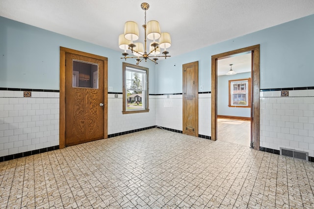 32 Franklin St, Southington, CT 06479 - unfurnished dining area with tile walls, a wainscoted wall, and a chandelier