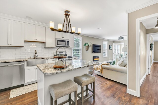 131 Long Hill Cross Rd, Shelton, CT 06484 - kitchen with stainless steel appliances, ornamental molding, tasteful backsplash, dark wood-style floors, and a breakfast bar area