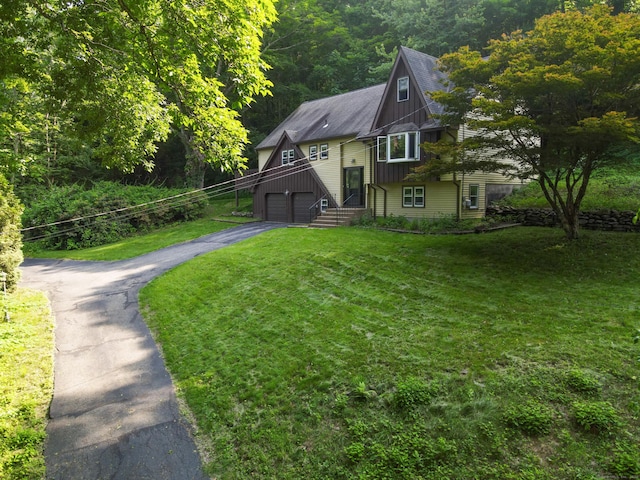 166 S Main St, Marlborough, CT 06447 - view of front of house with asphalt driveway, a front lawn, board and batten siding, an attached garage, and a wooded view