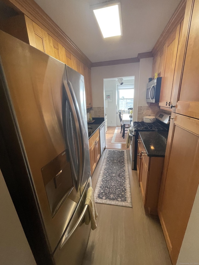 2625 Park Ave Unit 11P, Bridgeport, CT 06604 - kitchen with appliances with stainless steel finishes, dark countertops, light wood-style floors, crown molding, and backsplash