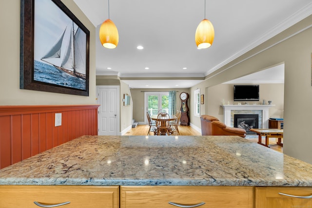 128 Holcomb Hill Rd, New Hartford, CT 06057 - kitchen with light stone counters, light wood-style flooring, crown molding, a glass covered fireplace, and open floor plan
