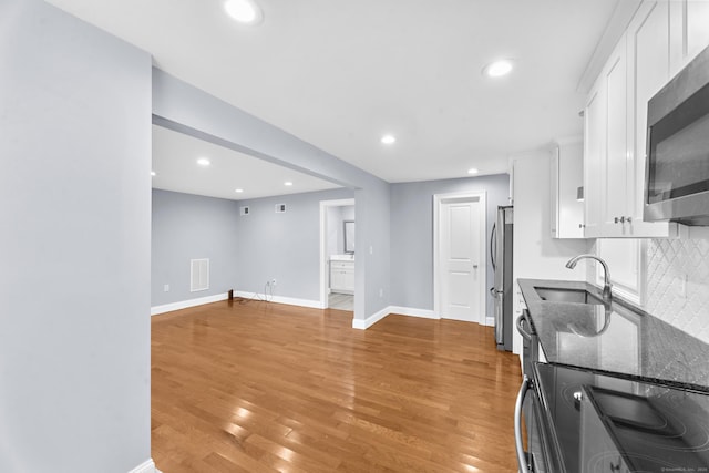 24 Main St, East Hampton, CT 06424 - kitchen with stainless steel appliances, white cabinets, dark stone counters, light wood-style flooring, and recessed lighting