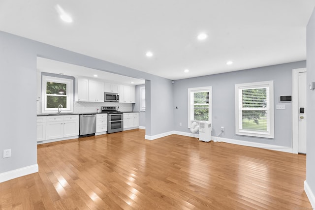 24 Main St, East Hampton, CT 06424 - kitchen featuring stainless steel appliances, light wood-type flooring, white cabinets, dark countertops, and decorative backsplash
