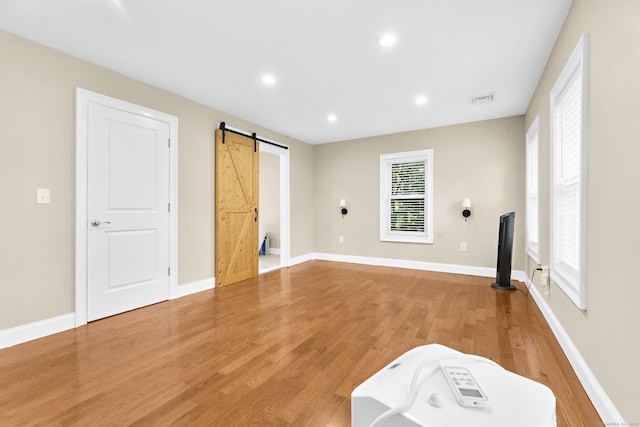 24 Main St, East Hampton, CT 06424 - unfurnished bedroom featuring a barn door, light wood finished floors, and recessed lighting