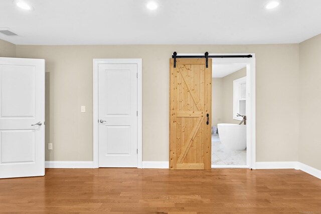 24 Main St, East Hampton, CT 06424 - unfurnished bedroom with recessed lighting, light wood-type flooring, and a barn door