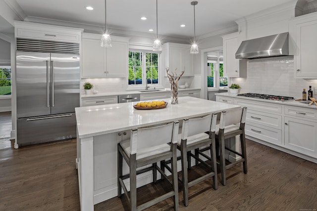 16 Gault Park Dr, Westport, CT 06880 - kitchen featuring appliances with stainless steel finishes, wall chimney exhaust hood, backsplash, white cabinetry, and dark wood finished floors