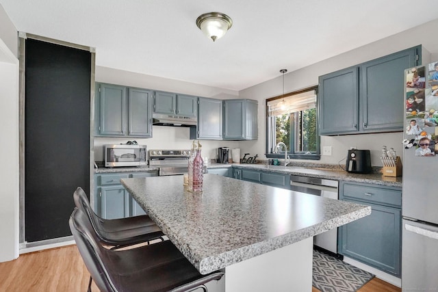 9 Renee Ln, Enfield, CT 06082 - kitchen with under cabinet range hood, stainless steel appliances, a breakfast bar, light wood-style flooring, and decorative light fixtures