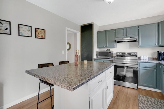 9 Renee Ln, Enfield, CT 06082 - kitchen with stainless steel appliances, under cabinet range hood, light wood finished floors, and a kitchen bar