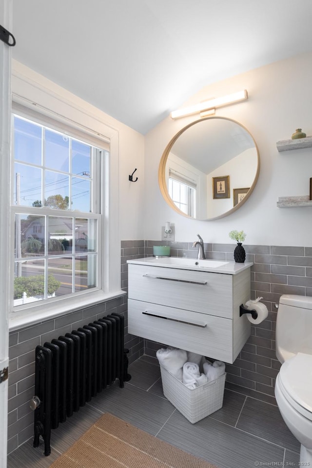 32 Holcomb St, West Haven, CT 06516 - bathroom featuring tile walls, radiator heating unit, tile patterned flooring, vanity, and a wainscoted wall