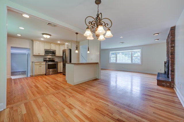 140 Braeside Dr, Hamden, CT 06514 - kitchen featuring appliances with stainless steel finishes, open floor plan, light wood-style flooring, a chandelier, and a fireplace