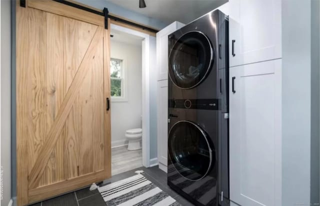 17 Kingsbury Rd, Norwalk, CT 06851 - washroom with stacked washer and clothes dryer, a barn door, and cabinet space
