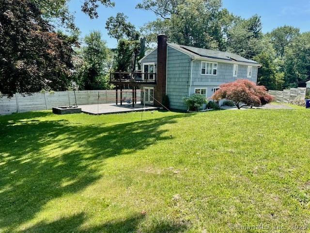17 Kingsbury Rd, Norwalk, CT 06851 - back of property with a deck, a fenced backyard, a chimney, a patio area, and view of wooded area