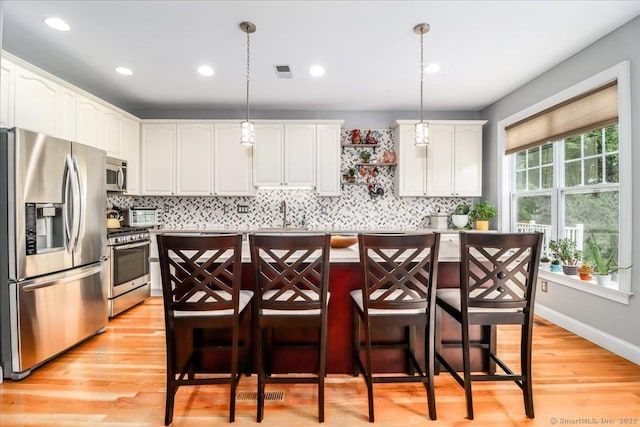 6 Faith Ln Unit 6, Danbury, CT 06810 - kitchen with stainless steel appliances, decorative backsplash, white cabinets, a breakfast bar area, and recessed lighting