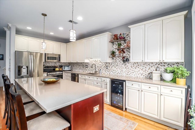 6 Faith Ln Unit 6, Danbury, CT 06810 - kitchen featuring appliances with stainless steel finishes, beverage cooler, a breakfast bar area, light wood-style flooring, and white cabinetry