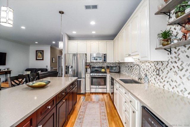 6 Faith Ln Unit 6, Danbury, CT 06810 - kitchen featuring stainless steel appliances, light wood-style flooring, ornamental molding, white cabinetry, and hanging light fixtures