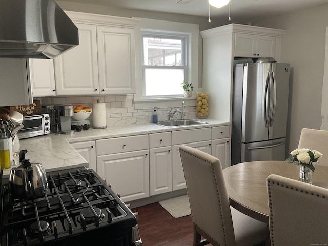 140 Stuart Ave, Norwalk, CT 06850 - kitchen featuring freestanding refrigerator, wall chimney exhaust hood, black range with gas cooktop, decorative backsplash, and white cabinetry