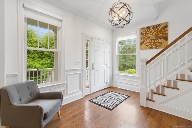 109 W Ave, Darien, CT 06820 - foyer entrance featuring a chandelier, stairs, wood finished floors, a decorative wall, and a wainscoted wall