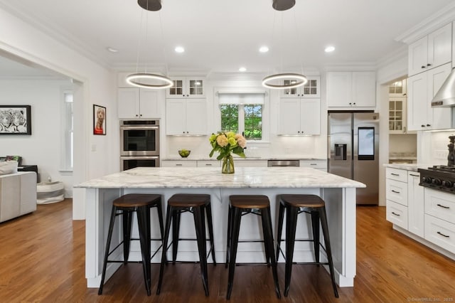 109 W Ave, Darien, CT 06820 - kitchen featuring stainless steel appliances, ornamental molding, a center island, a kitchen breakfast bar, and white cabinets