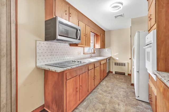 165 Douglas St, Stratford, CT 06614 - kitchen with appliances with stainless steel finishes, backsplash, radiator heating unit, light stone countertops, and brown cabinetry
