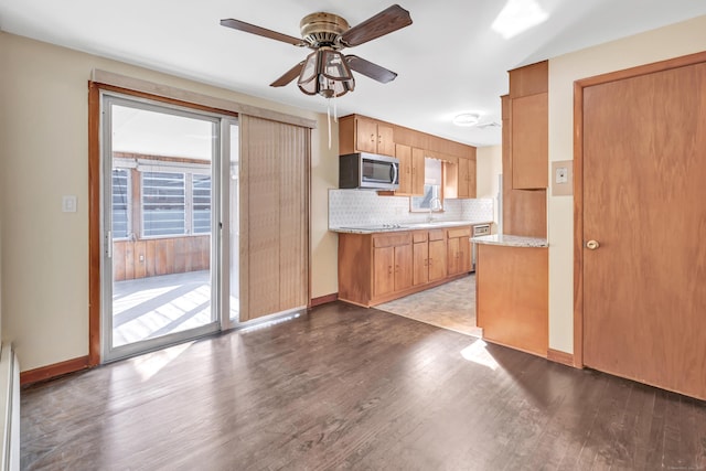165 Douglas St, Stratford, CT 06614 - kitchen featuring stainless steel microwave, light countertops, a ceiling fan, decorative backsplash, and wood finished floors