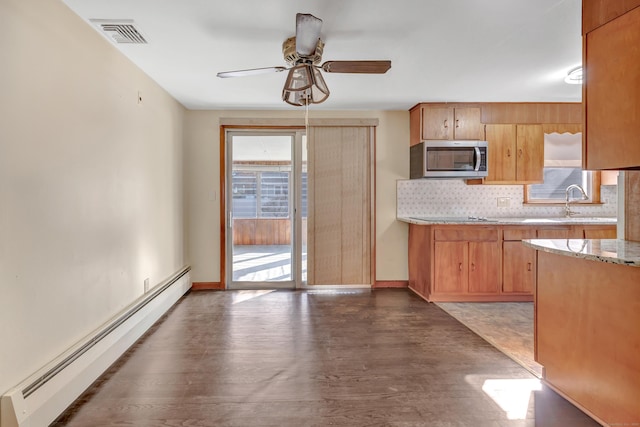 165 Douglas St, Stratford, CT 06614 - kitchen featuring stainless steel microwave, baseboard heating, a ceiling fan, tasteful backsplash, and wood finished floors