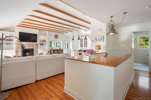113 N Lake Shore Dr, Brookfield, CT 06804 - living area with vaulted ceiling, wood finished floors, a stone fireplace, built in shelves, and wainscoting