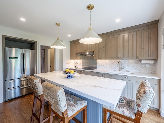 120 Prospect St Apt 63, Ridgefield, CT 06877 - kitchen with stainless steel fridge, under cabinet range hood, backsplash, a kitchen breakfast bar, and dark wood-style floors