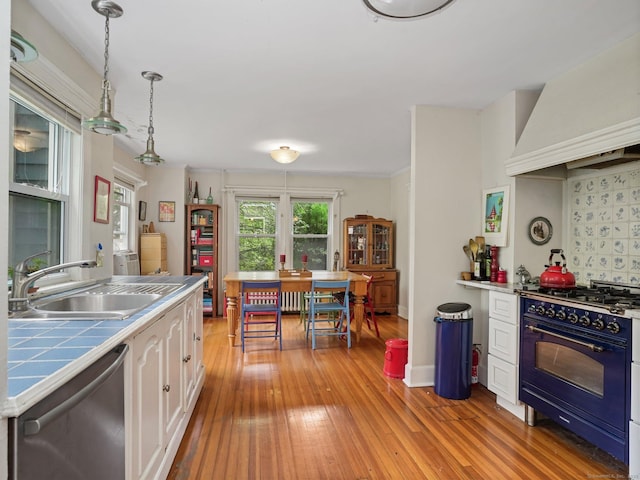 58 Riverdale Ave, Greenwich, CT 06831 - kitchen with dishwasher, black gas range oven, tile counters, white cabinetry, and premium range hood