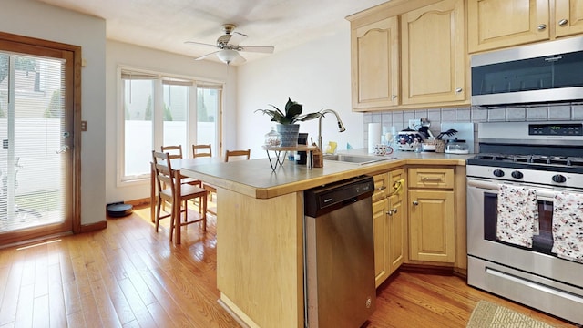 279 New Haven Ave Apt E, Milford, CT 06460 - kitchen with stainless steel appliances, light brown cabinetry, a peninsula, and plenty of natural light