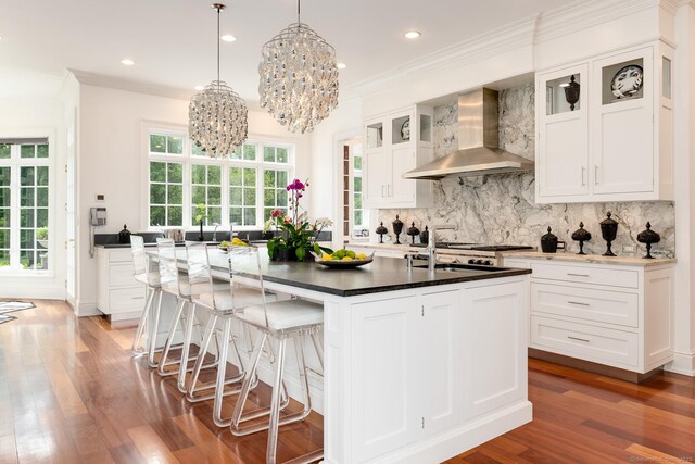 474 Ponus Rdg, New Canaan, CT 06840 - kitchen featuring wall chimney range hood, a chandelier, wood finished floors, ornamental molding, and backsplash
