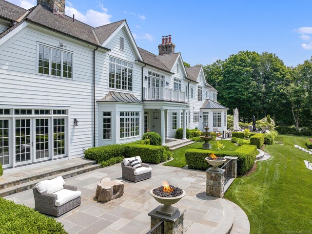474 Ponus Rdg, New Canaan, CT 06840 - back of house featuring a chimney, a patio, a balcony, a standing seam roof, and french doors