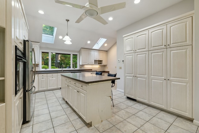 24 Quince Ct, Bristol, CT 06010 - kitchen featuring a skylight, dark countertops, light tile patterned floors, white cabinets, and ceiling fan