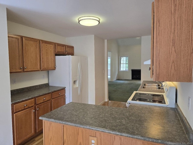 244 Oakland St Apt F, Manchester, CT 06042 - kitchen featuring white fridge with ice dispenser, stove, dark countertops, a peninsula, and brown cabinets