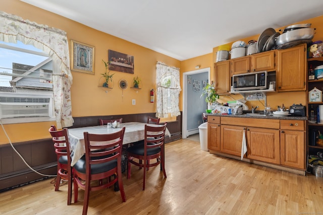 83 James St, New Haven, CT 06513 - kitchen featuring stainless steel microwave, light wood-type flooring, brown cabinetry, a wainscoted wall, and dark countertops