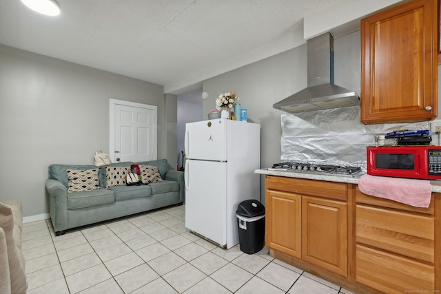 83 James St, New Haven, CT 06513 - kitchen with wall chimney range hood, freestanding refrigerator, stainless steel gas cooktop, light countertops, and light tile patterned floors