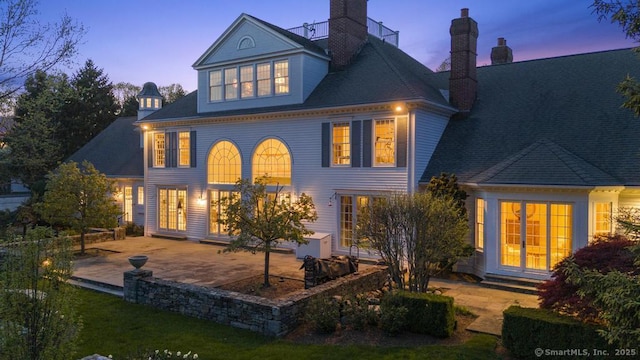 21 Queens Grant Dr, Fairfield, CT 06824 - back of house at dusk featuring a patio and a chimney