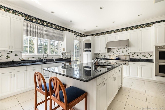 21 Queens Grant Dr, Fairfield, CT 06824 - kitchen with under cabinet range hood, appliances with stainless steel finishes, light tile patterned flooring, white cabinets, and decorative backsplash