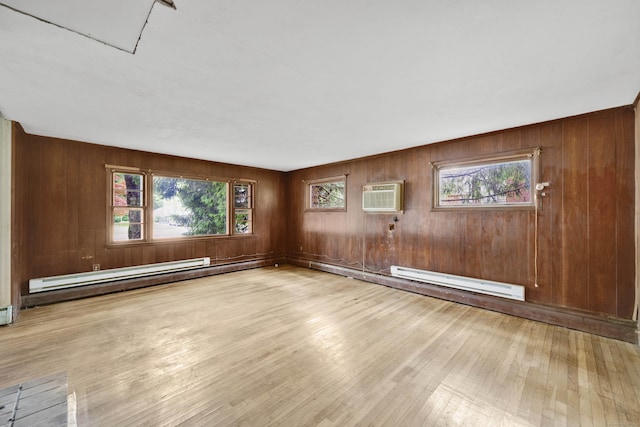 134 Sunset St, Windsor Locks, CT 06096 - empty room featuring a wall unit AC, wood finished floors, a baseboard radiator, plenty of natural light, and wood walls