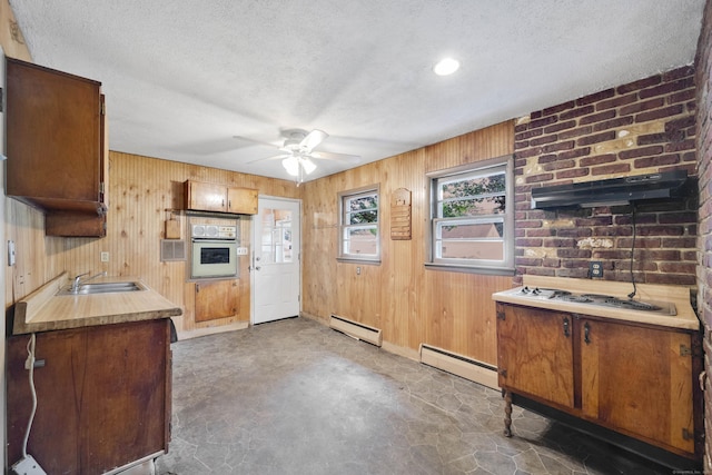 134 Sunset St, Windsor Locks, CT 06096 - kitchen featuring baseboard heating, wood walls, white appliances, ceiling fan, and a textured ceiling