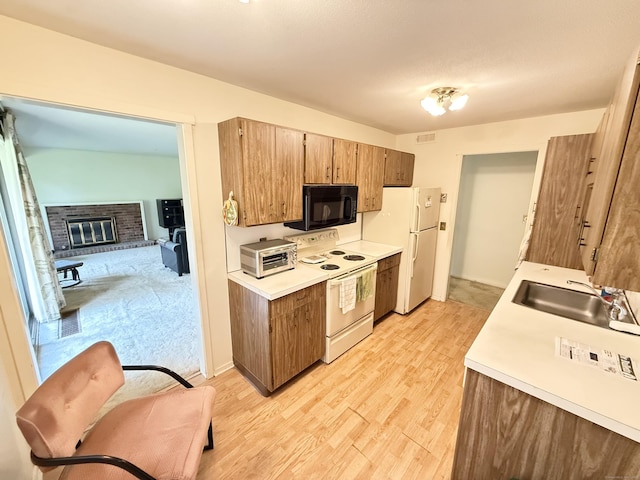32 Heritage Vlg Unit C, Southbury, CT 06488 - kitchen with white appliances, light countertops, light wood finished floors, and a fireplace