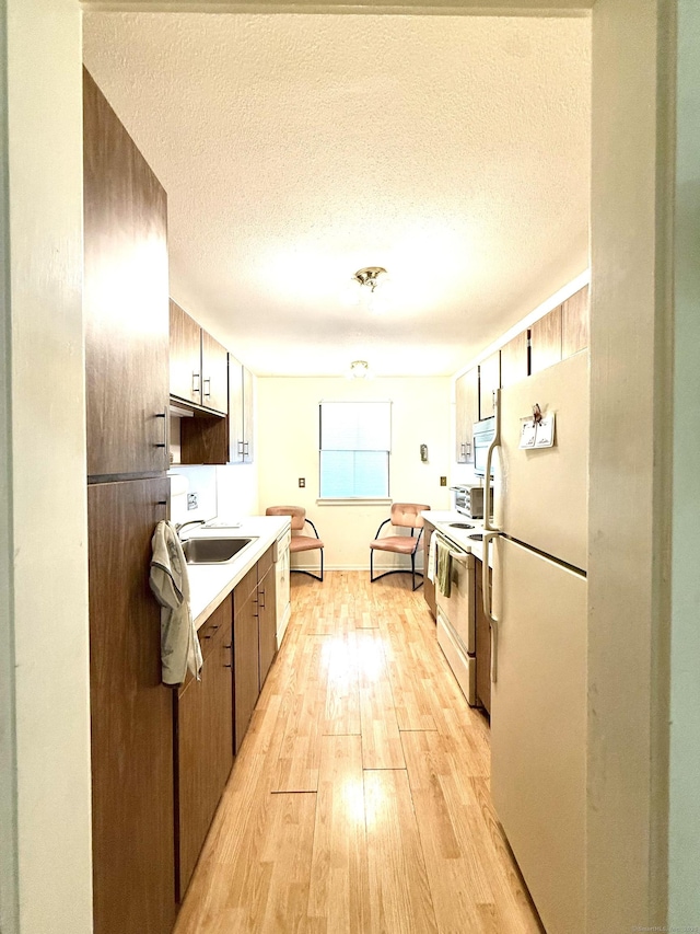 32 Heritage Vlg Unit C, Southbury, CT 06488 - kitchen featuring white appliances, light wood-style flooring, a textured ceiling, and light countertops