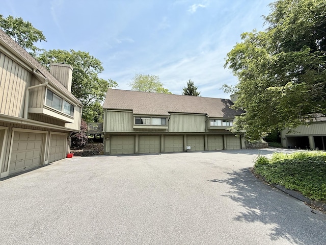 32 Heritage Vlg Unit C, Southbury, CT 06488 - view of front facade featuring community garages, a chimney, and a shingled roof