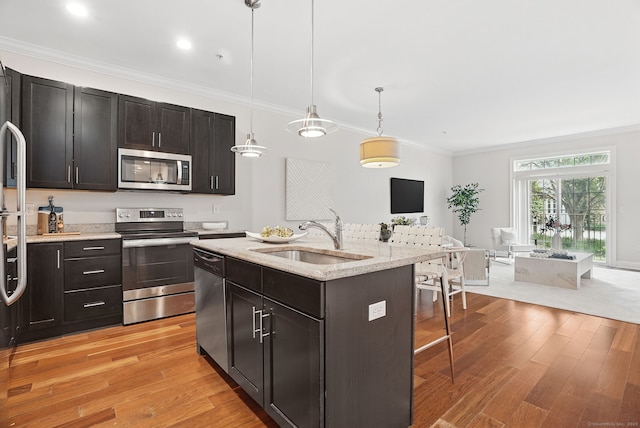 142 E Ave Unit A106, Norwalk, CT 06851 - kitchen featuring stainless steel appliances, light wood-style floors, a breakfast bar area, ornamental molding, and light stone countertops