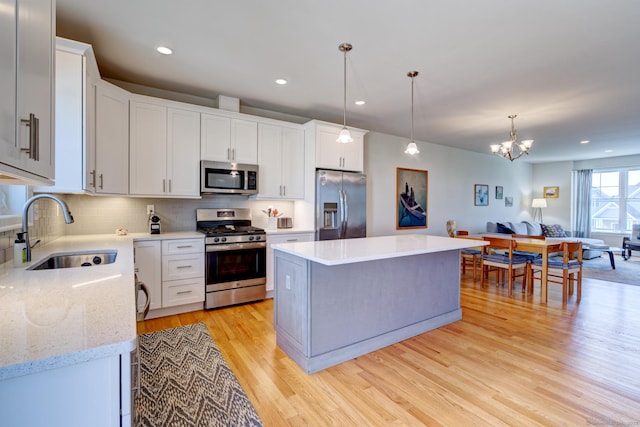 48 Park Ave Unit 48, Stonington, CT 06355 - kitchen featuring appliances with stainless steel finishes, light wood finished floors, a kitchen island, decorative backsplash, and a chandelier