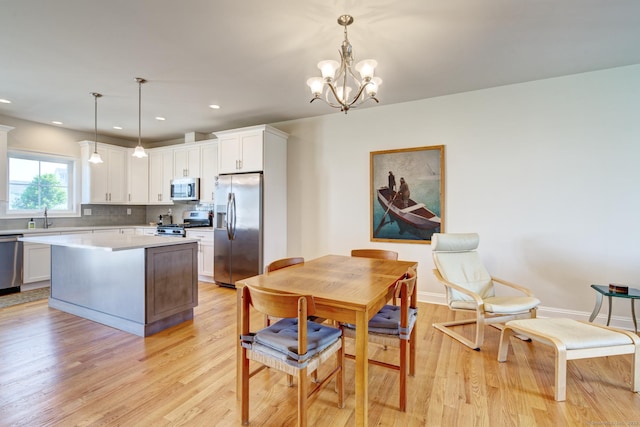 48 Park Ave Unit 48, Stonington, CT 06355 - kitchen with stainless steel appliances, light wood finished floors, light countertops, a chandelier, and decorative backsplash