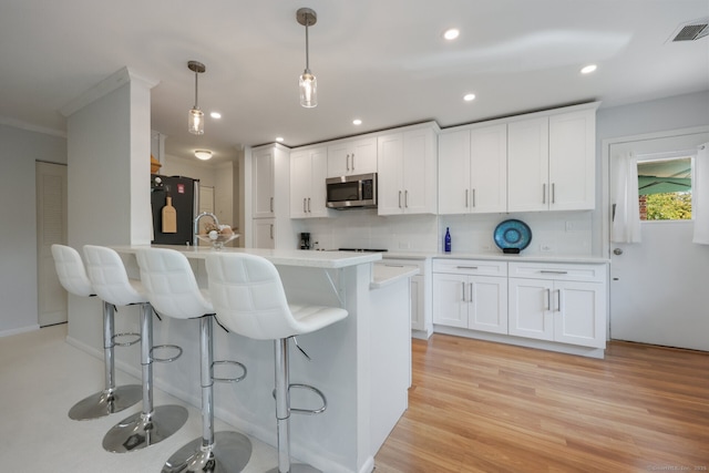 195 Southport Woods Dr Unit 195, Fairfield, CT 06890 - kitchen with appliances with stainless steel finishes, a breakfast bar area, backsplash, light countertops, and white cabinetry