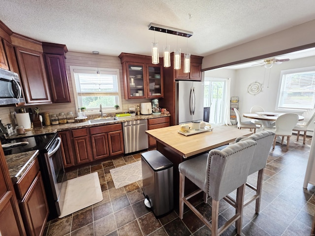 23 Teach St, Enfield, CT 06082 - kitchen featuring appliances with stainless steel finishes, healthy amount of natural light, a textured ceiling, a breakfast bar, and ceiling fan
