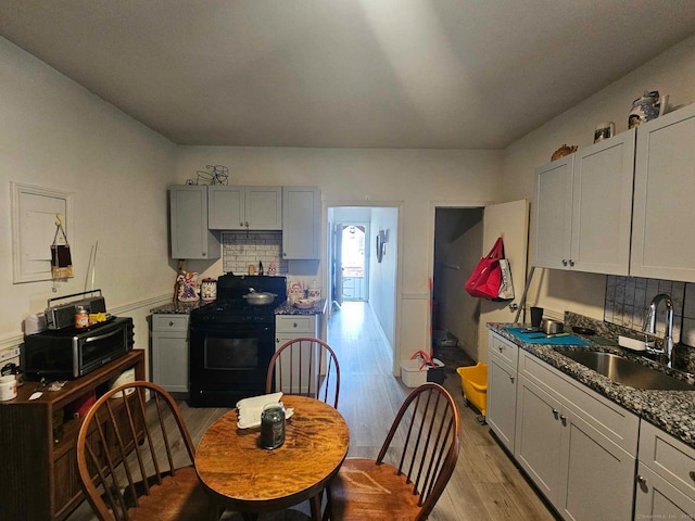 763 Park St, Hartford, CT 06106 - kitchen with black appliances, light wood-type flooring, tasteful backsplash, and dark countertops